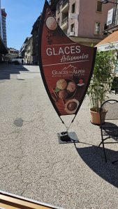 Oriflamme publicitaire pour des glaces artisanales dans une rue de La Chaux-de-Fonds.
